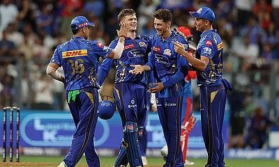 Mumbai Indians' Mitchell Santner celebrates with teammates after taking the caught and bowled wicket of Delhi Capitals' Vipraj Nigam alt=