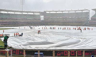 Covers are placed on the pitch as it rains during the ICC Men's Cricket World warm-up match between India and England in Guwahati on Saturday